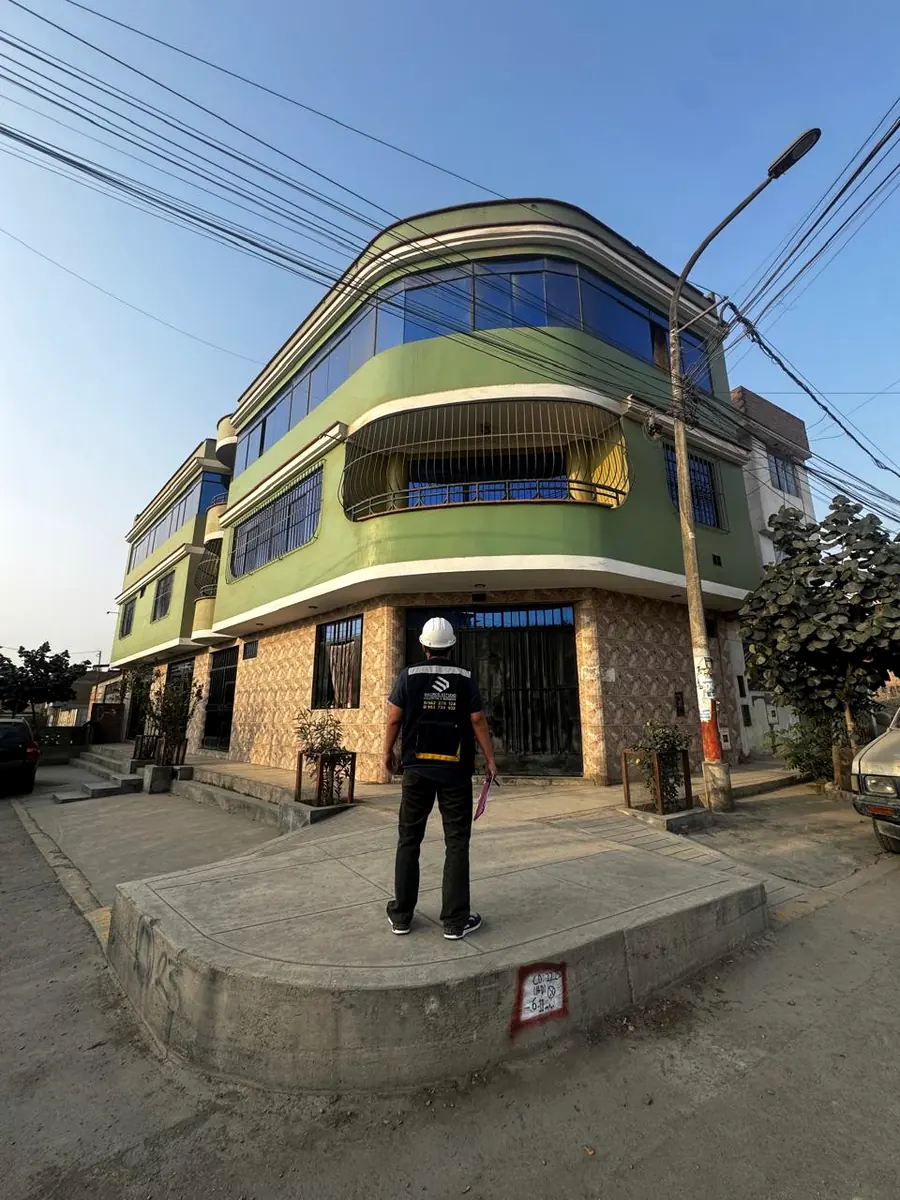 Supervisor con casco frente a un edificio de tres pisos