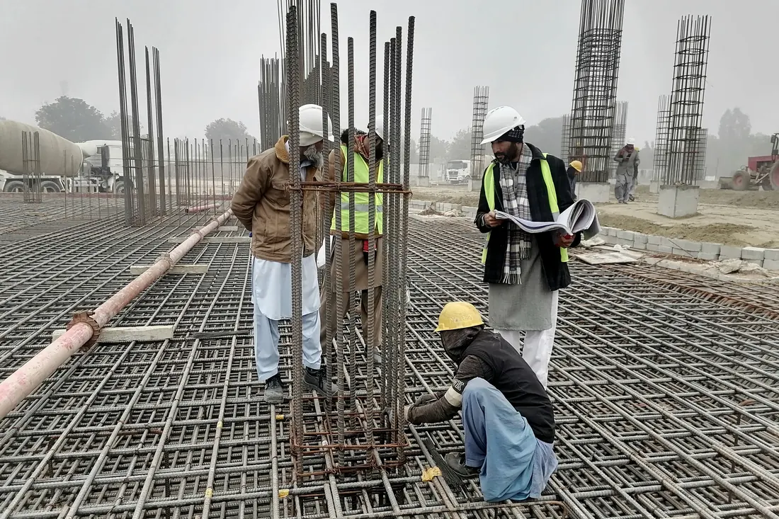 Profesionales revisando planos sobre el fierro de una losa