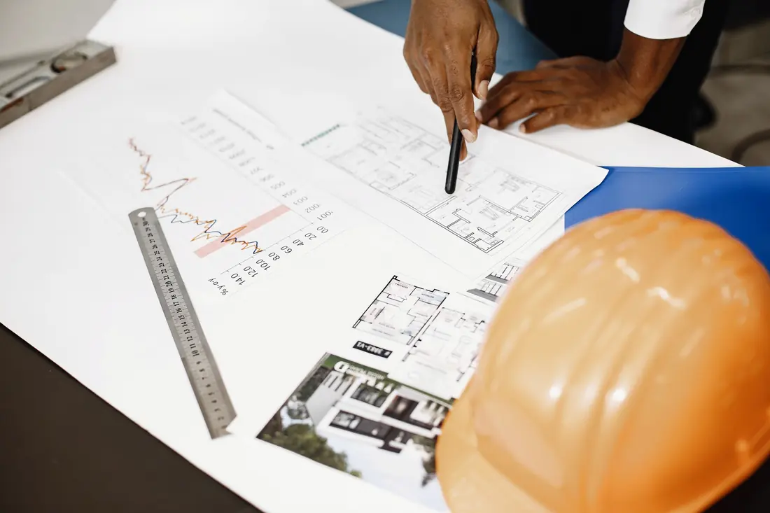 Planos de arquitectura con casco y regla sobre la mesa