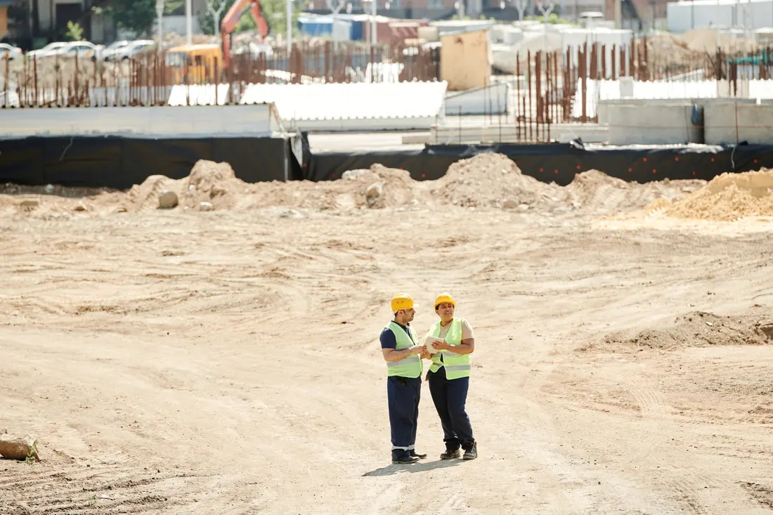 Dos profesionales con chaleco supervisando un terreno